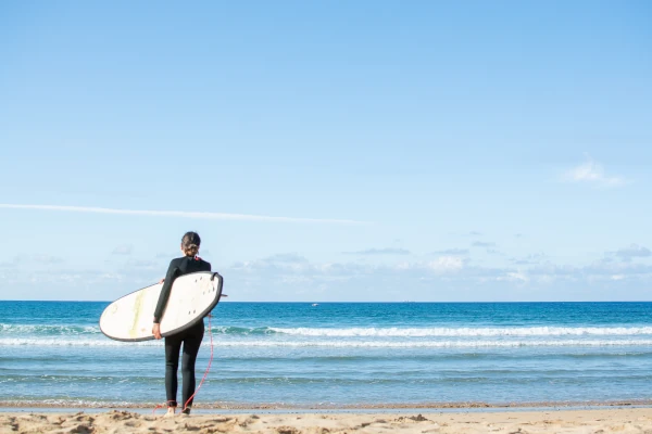 Une femme tenant une planche de surf sur une plage